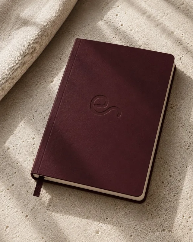 Cuaderno granate con el símbolo de EP Studio marcado en seco